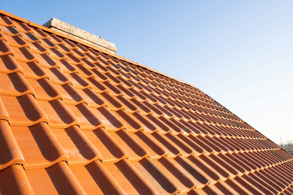 Overlapping rows of yellow ceramic roofing tiles covering residential building roof